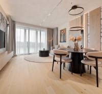 A living room with a marble wall, a television, and a dining table in a three-room apartment.