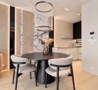 Dining room in a 3-room apartment with a round table, wooden decorations, and an open kitchen.