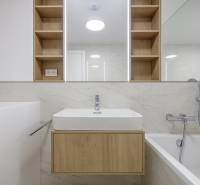 A bathroom in a 3-room apartment with a bathtub, sink, and wooden details.
