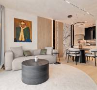 Living room with a sofa, round table, painting, and dining area in a three-room apartment.