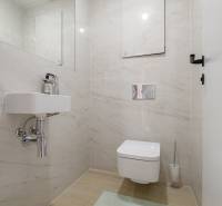 Bathroom with wall-mounted toilet, sink, and tiles in a 3-room apartment.