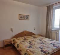 Bedroom in a 4-room apartment with a double bed, a painting, and balcony doors.