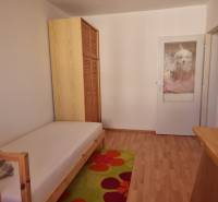 A simple room with a bed, a wooden wardrobe, and a colorful carpet in a 4-room apartment.