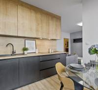 A kitchen in a 2-room apartment with wooden cabinets, a dining table with flowers.