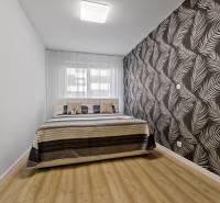 A bedroom with a bed and patterned wallpaper in a 2-room apartment.