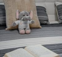 A toy elephant on a pillow with a book on a bed in a 2-room apartment.