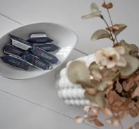 A bowl of candies Dr. Domov next to a vase with flowers on the table in a 2-room apartment.