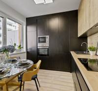 A kitchen in a 2-room apartment with a dining table and a modern black kitchen unit.