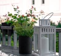 A white lantern with a flower pot on a table in a 2-room apartment.