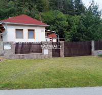 A cottage in Helcmanovce with a wooden fence and a manicured lawn surrounded by greenery.