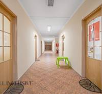 A corridor with doors, tiles, and a green chair in offices.