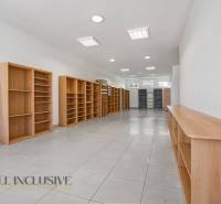 A space with light walls and wooden shelves has plenty of natural light.