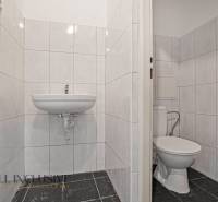 A restroom in commercial premises with white tiles and a sink.