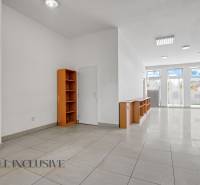 Commercial spaces with white walls and shelves, tiled floor, large windows.