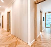A hallway in a 4-room apartment with a wooden floor and a view into a room.