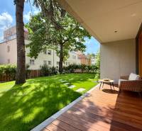 Terrace with a garden by a 4-room apartment, trees and buildings in the background.