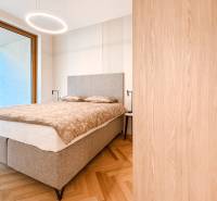 A bedroom with a gray bed, built-in wardrobe, parquet floors, and a view in a 4-room apartment.
