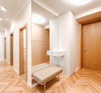 A spacious hallway with a mirror and a bench in a 4-room apartment with wooden doors.