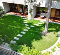 Garden terrace of a 4-room apartment with a lawn and wooden furniture.