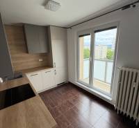 A kitchen in a 2-room apartment with a wooden countertop and access to a balcony.