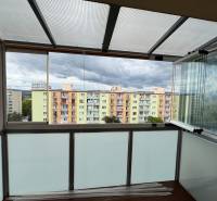 A glazed balcony with a view of colorful apartment buildings on SNP Street in Nová Dubnica.