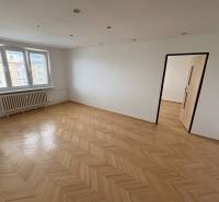 A room with a parquet floor, white walls, and windows, part of a 2-room apartment.