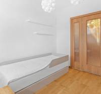 A bedroom in a 4-room apartment with a single bed, wooden floor, and light-colored doors.