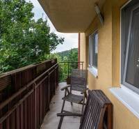 A balcony with chairs in a 4-room apartment overlooking greenery.