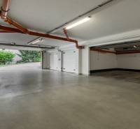 Parking space in a 4-room apartment with open garage doors and pipes on the ceilings.