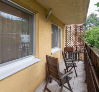Balcony of a 4-room apartment with wooden furniture and a green view.