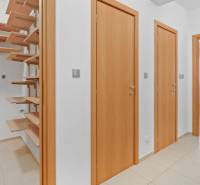 Hallway with wooden doors, shelves, and entrance to a room in a 4-room apartment.