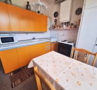 The kitchen of a 2-room apartment with yellow cabinets and a dining table.