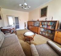 Living room in a 2-room apartment with a bookshelf, a sofa set, and a table with chairs.