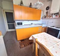 A kitchen with an orange countertop and a dining table in a 2-room apartment.