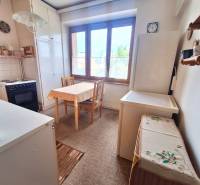 A kitchen in a 2-room apartment with a wooden dining table and a large window.