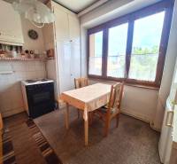 A kitchen in a 2-room apartment with a table, chairs, a stove, and a large window.