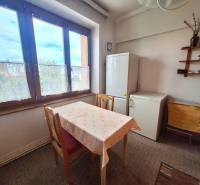 Dining room of a 2-room apartment with a table, refrigerator, and a display cabinet on the wall.