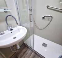 A bathroom in a 2-room apartment with a sink, shower, and laminate flooring.