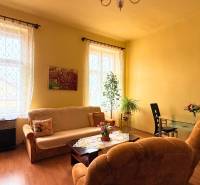 Living room in a family house with light furniture, flowers, and a dining table.