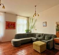 Living room in a family house with a corner sofa, wooden floor, and decorations.