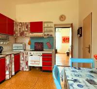 A kitchen in a family house with red cabinets, a table, and flowers in a vase.