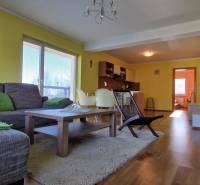 Living room in a holiday apartment with a sofa, table, and kitchenette.