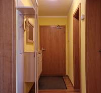 A corridor with wooden doors, yellow walls, and a coat rack system in a Holiday Apartment.