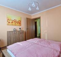 Bedroom in a Holiday Apartment with a bed, wardrobe, armchair, and a painting of flowers.