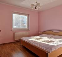 Bedroom in a Holiday Apartment with wooden floor, pink walls, and a bed.