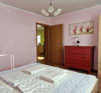 Bedroom in a vacation apartment with a wardrobe, a red dresser, and a flower painting.