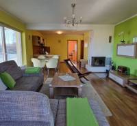 Living room in a holiday apartment with a sofa, television, fireplace, and kitchenette.