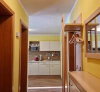 Hallway with a shoe cabinet, mirror, and a view into the kitchen in a recreational apartment.