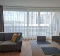 Living room of a 3-room apartment with a sofa, dining table, and a view of the balcony.