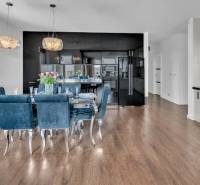 A kitchen in a 4-room apartment with dark cabinets, a dining table, and wooden flooring.